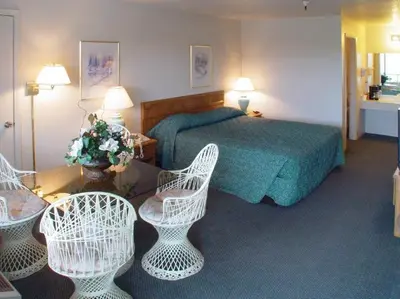 a hotel room with a bed and two chairs at Applegate Inn in Atwater