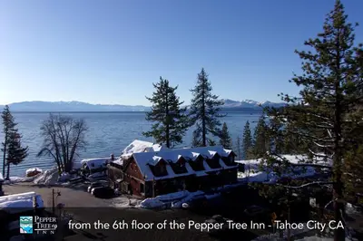 a house on the shore of a lake with snow on it at Pepper Tree Inn Tahoe City in Tahoe City