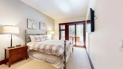 a bedroom with a bed and a tv on a wall at Juniper Crest #25 Condo in Mammoth Lakes