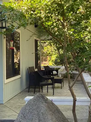 a patio with chairs and a table and a tree at Kin House Guest Suite in Oakhurst