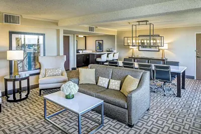 a living room with a couch and a kitchen at Hilton Sacramento Arden West in Sacramento