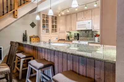 a kitchen with wooden cabinets and a counter with stools at Mountainback 80 in Mammoth Lakes