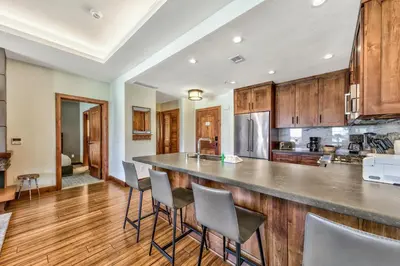 a kitchen with wooden cabinets and a bar with stools at Luxury 2Br Residence Steps From Heavenly Village & Gondola Condo in South Lake Tahoe