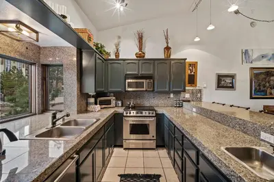 a kitchen with green cabinets and stainless steel appliances at Mammoth Village Properties by 101 Great Escapes in Mammoth Lakes