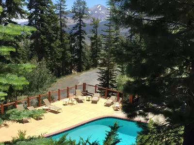 a pool with chairs and a deck with a mountain at Timber Ridge Resort by 101 Great Escapes in Mammoth Lakes