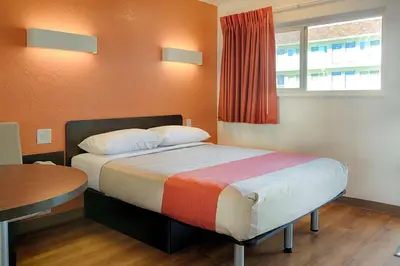 a bedroom with a bed and a table and a window at Motel 6-Mammoth Lakes, CA in Mammoth Lakes