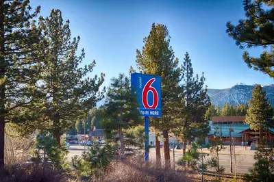 a sign for a gas station in front of trees at Motel 6-Mammoth Lakes, CA in Mammoth Lakes