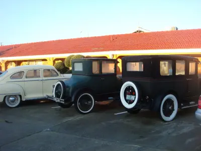 two old cars parked next to each other in a parking lot at Economy Inn Los Banos in Los Banos