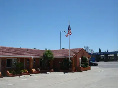 a hotel with an american flag in a parking lot at Economy Inn Los Banos in Los Banos