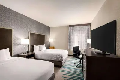 a hotel room with two beds and a flat screen tv at La Quinta by Wyndham Clovis CA in Clovis