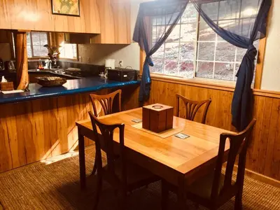 a kitchen with a wooden table with chairs and a window at A Lovely Cabin House at Way Woods Retreat with Outdoor Hot Tub! - By Sacred Hub MGMT in Foresthill