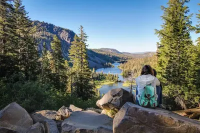 a woman sitting on a rock overlooking a lake at Chateau Blanc 23 in Mammoth Lakes