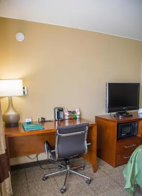 a room with a desk with a chair and a television at Quality Inn Merced Gateway to Yosemite in Merced