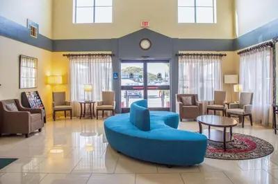 a waiting room with a blue couch and chairs at Quality Inn Merced Gateway to Yosemite in Merced