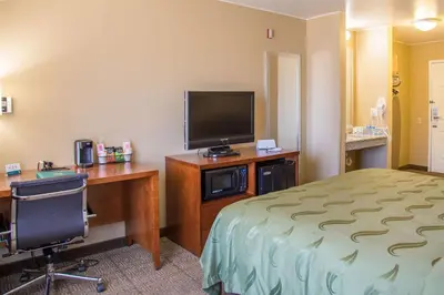 a hotel room with a bed and a desk with a television at Quality Inn Merced Gateway to Yosemite in Merced