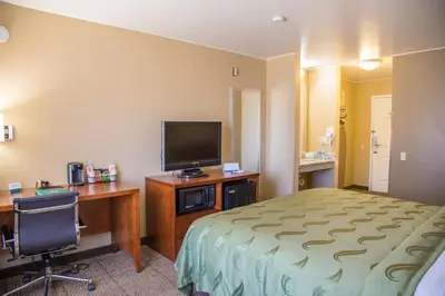 a hotel room with a bed and a desk and a television at Quality Inn Merced Gateway to Yosemite in Merced