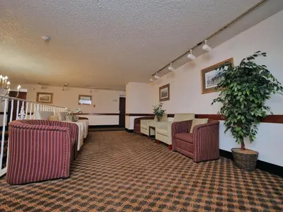 a waiting room with two chairs and a plant at Red Lion Inn & Suites Auburn in Auburn