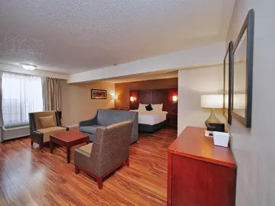 a hotel room with a bed and a living room at Red Lion Inn & Suites Auburn in Auburn