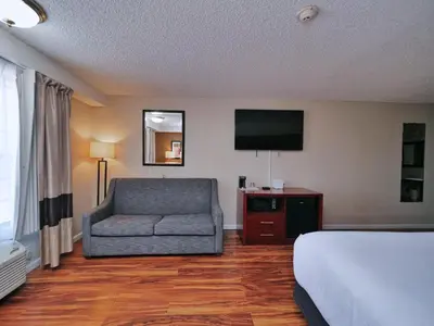 a hotel room with a bed and a couch and a television at Red Lion Inn & Suites Auburn in Auburn