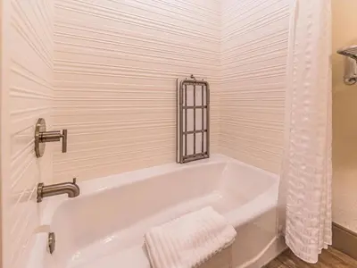 a white bath tub in a bathroom at The Hanford Hotel, an Ascend Collection Hotel in Hanford