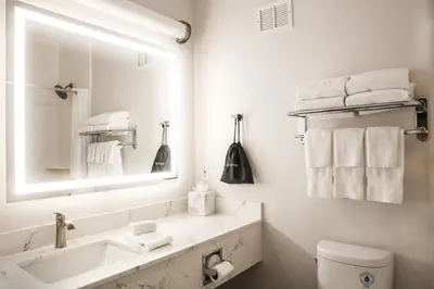 a white bathroom with a sink and a mirror at The Hanford Hotel, an Ascend Collection Hotel in Hanford