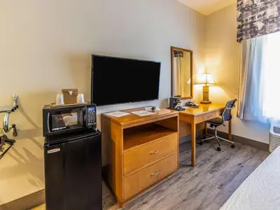 a hotel room with a tv and a desk with a computer at The Hanford Hotel, an Ascend Collection Hotel in Hanford