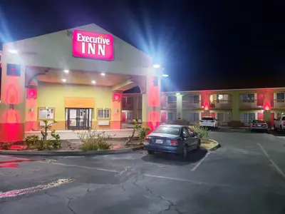 a shopping inn with a car parked in a parking lot at Executive Inn westley,CA in Westley