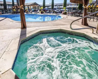 a swimming pool with water in it with an umbrella at Quality Inn & Suites Cameron Park Shingle Springs in Cameron Park