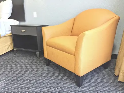 a yellow chair in a room with a bed and a nightstand at Quality Inn & Suites South San Jose - Morgan Hill in Morgan Hill