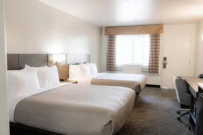 a hotel room with two beds and a desk at Quality Inn & Suites Lathrop in Lathrop