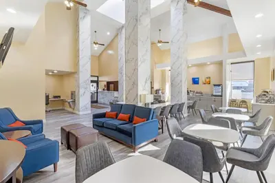 a lobby with blue chairs and tables and a kitchen at Comfort Inn & Suites Near Fallon Naval Air Station in Fallon