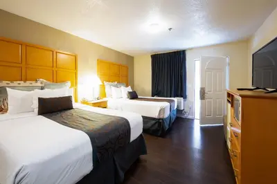a hotel room with two beds and a flat screen tv at Signature Inn Merced Yosemite Parkway in Merced