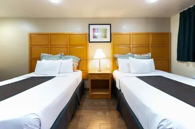 a hotel room with two beds and a lamp at Signature Inn Merced Yosemite Parkway in Merced