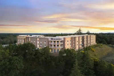 an apartment building on top of a hill with a sunset at Hotel Vista Sierra in Auburn