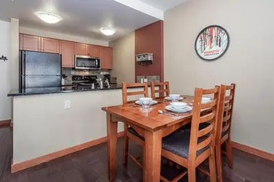 a kitchen with a wooden table with chairs and a refrigerator at Village 3211 in Mammoth Lakes
