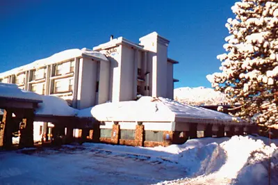 a snow covered building with a tree in front of it at Shilo Inn Mammoth Lakes in Mammoth Lakes