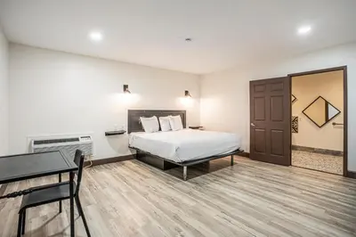 a hotel room with a bed and a desk and a table at The Greens Hotel on Stockton in Sacramento