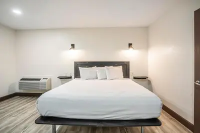 a bedroom with a large bed with white sheets at The Greens Hotel on Stockton in Sacramento