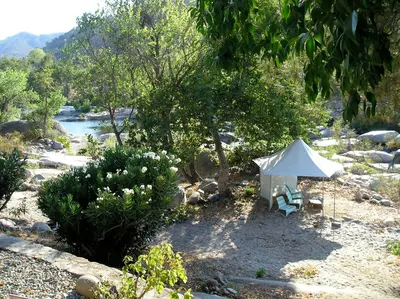 a white tent and a bench next to a river at Rio Sierra Riverhouse in Three Rivers