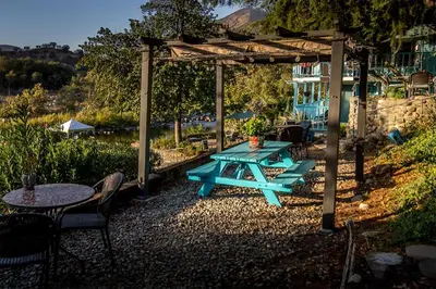 a picnic table under a pergola with tables and chairs at Rio Sierra Riverhouse in Three Rivers
