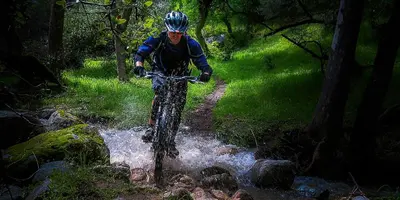 a man riding a bike through a stream at Rio Sierra Riverhouse in Three Rivers