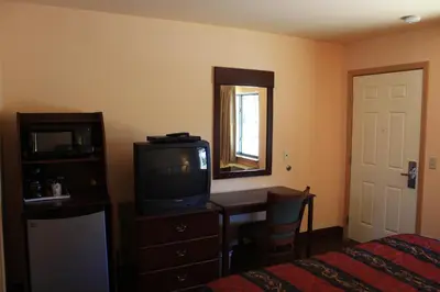 a bedroom with a tv and a desk and a bed at Gold Trail Motor Lodge in Placerville