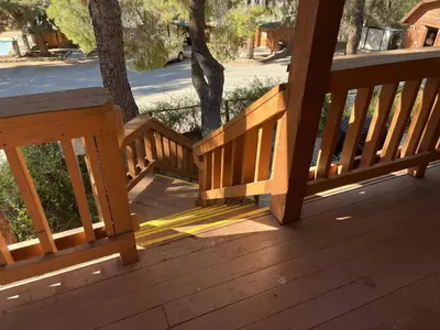 a wooden railing on a porch with a tree at Whispering Pines Lodge in Kernville