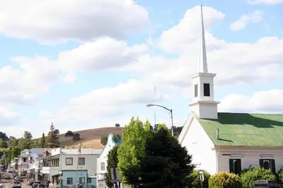 a white church with a steeple on a city street at Eureka Street Inn in Sutter Creek