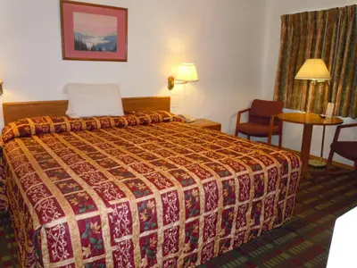 a hotel room with a bed and a table and a chair at Value Inn in Fallon