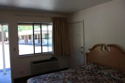 a bedroom with a bed and a large window at Mother Lode Motel in Placerville