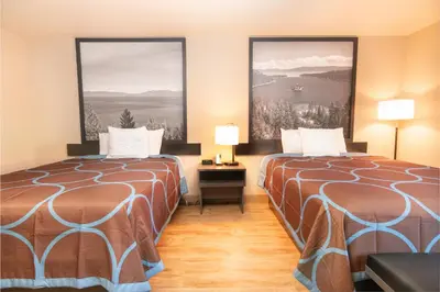 two beds in a hotel room with two large windows at Super 8 by Wyndham Fallon in Fallon