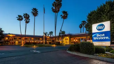 a hotel with a best western sign and palm trees at Best Western Apricot Inn in Chaney Ranch