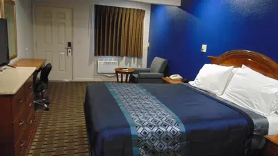 a hotel room with a bed with a blue wall at Corcoran Country Inn in Corcoran