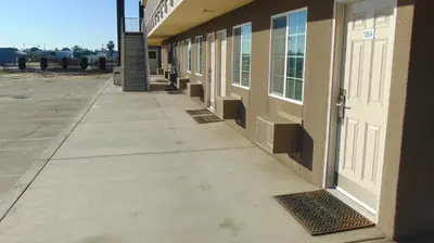 a sidewalk next to a building with a white door at Corcoran Country Inn in Corcoran